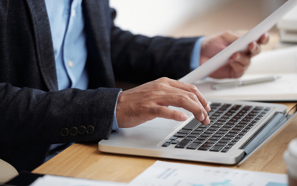 man typing while checking his notes on website design RFP template